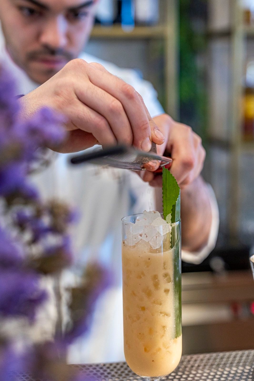 Bartender preparing a cocktail with crushed ice and mint at OIKOS